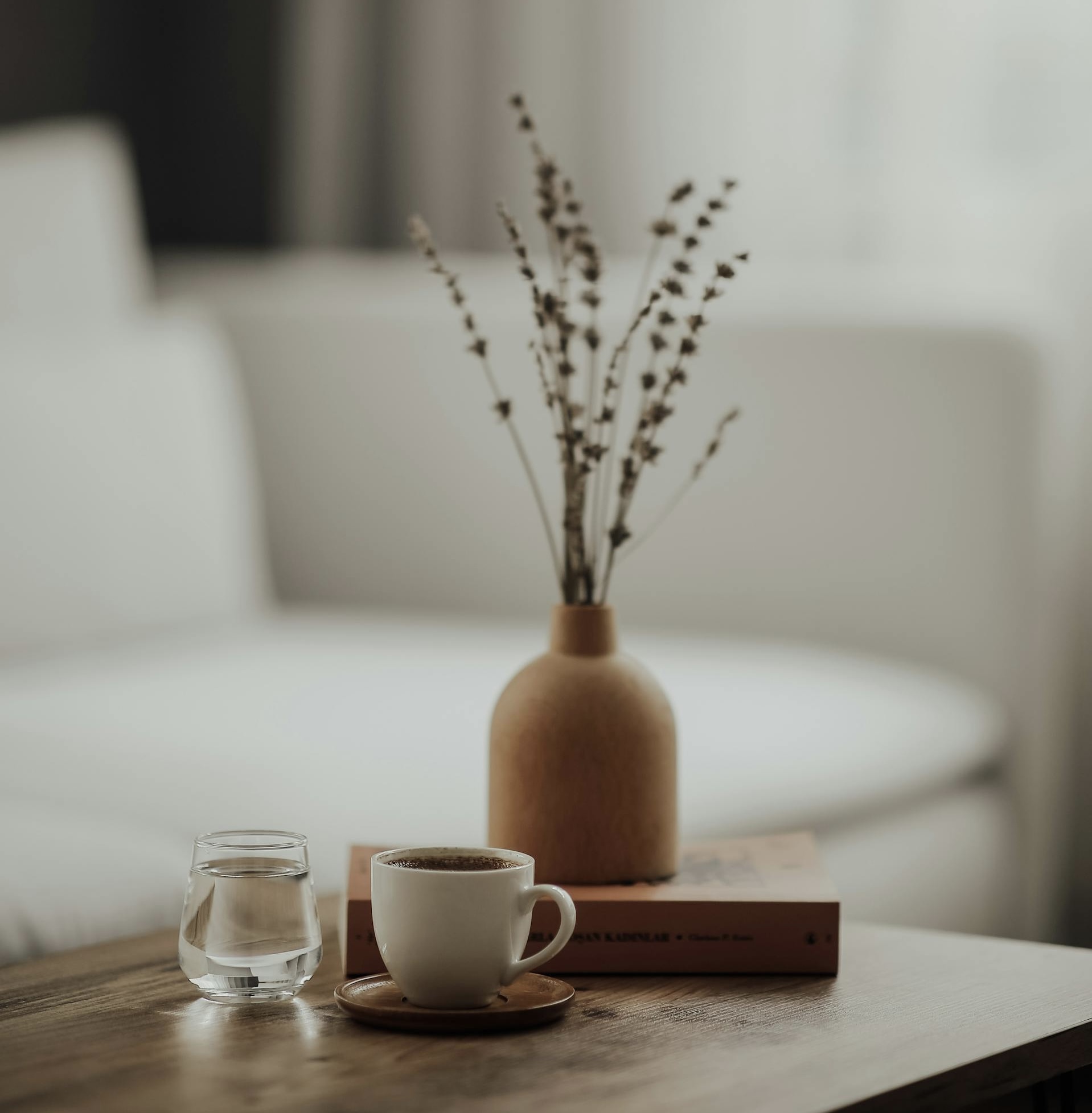 Warm home styling — coffee cup, vase and books on a wooden table